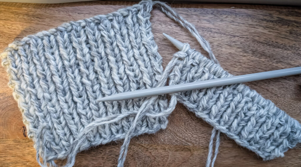 1 Chunky Wrist Warmer knitted and the other on the needles